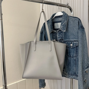 Primer plano de un bolso tote minimalista de piel sintética gris claro en una percha