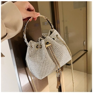 Close-up of sparkling silver rhinestone bucket bag with golden metal ring handle and chain