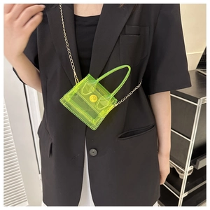 Mini sac transparent vert néon avec chaîne dorée porté sur un blazer noir élégant