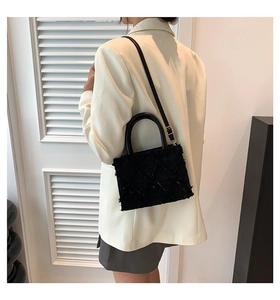 Fashionable black quilted fringe crossbody bag worn with an elegant beige blazer