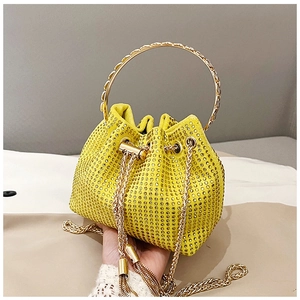 Detail of yellow rhinestone bucket bag with gold ring handle and metallic tassels