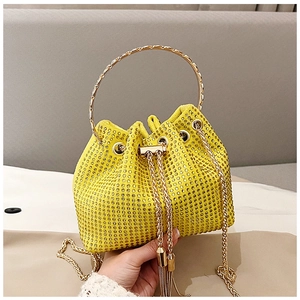 Detailed view of yellow bucket bag with sparkling rhinestones, gold ring handle and tassels
