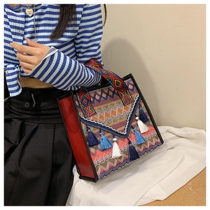 Dettaglio della borsa tote intrecciata boho con nappe colorate e motivi etnici ricamati