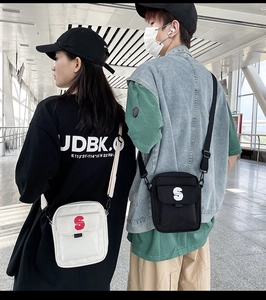Bandolera de nailon de estilo urbano con parche de letra S en un modelo en una estación
