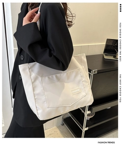 Detailed view of white canvas tote bag featuring front pocket with fashion label and sleek design