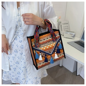 Dettaglio della borsa tote etnica intrecciata con nappe colorate e trame geometriche