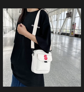 Vista de cerca del bolso bandolera de nylon blanco con logo S rojo y correa ancha
