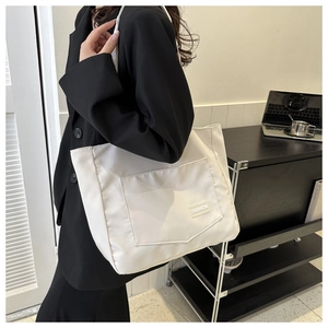 Close-up of white large capacity nylon tote bag with a fashion label and front pocket detail