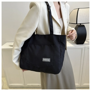 Close-up of black nylon tote bag with fashion label showing durable shoulder strap detail