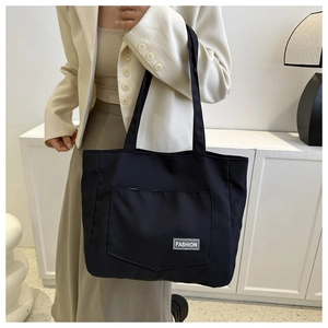 Detail of a large black nylon tote bag with Fashion label shown on a female model