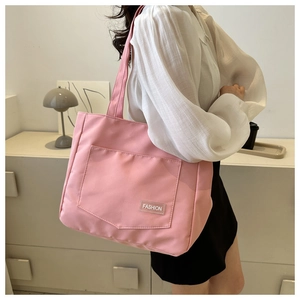 Detail of pink nylon tote bag with front pocket and fashion label on a model