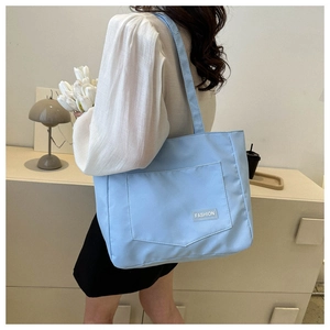 Close-up of light blue nylon tote bag with exterior pocket and white fashion label detail