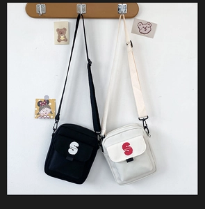 Detalle de bolsos bandolera de lona en negro y beige con correas ajustables