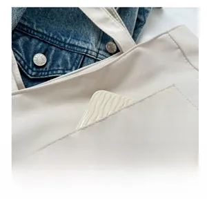 Close-up of front pocket on off-white nylon tote bag with a phone case inside for detail