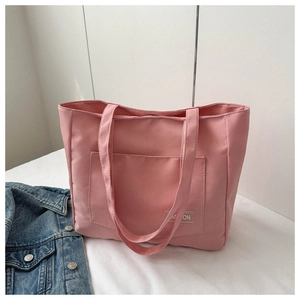 Pink nylon tote bag detail with front pocket and fashion label on clean white background