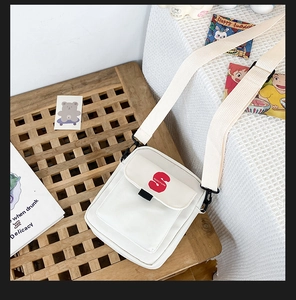 Detalle del bolso bandolera de lona blanca con estampado S rojo y correa ancha