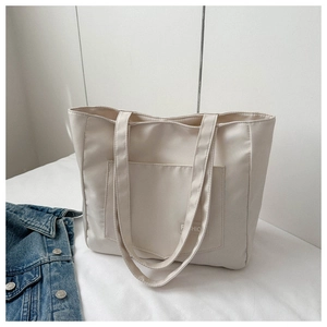 Detail shot of a beige nylon tote bag with a front pocket and stylish fashion label