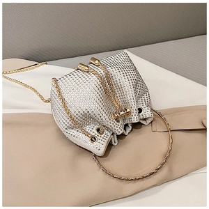 Detailed view of silver rhinestone bucket bag featuring gold metal ring handle and chain