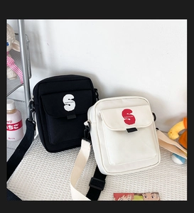 Detalle de bolsos bandolera minimalistas de nailon en blanco y negro con logo en la correa