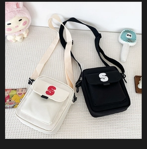Detalle de bolsos bandolera de nailon en blanco y negro con bolsillo delantero con solapa