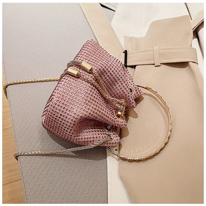 Close-up of pink rhinestone bucket bag with golden ring handle and drawstring detail