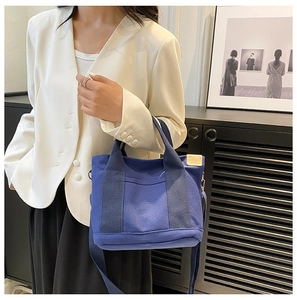 Detailed macro view of dark blue canvas tote bag with side leather trim and silver hardware