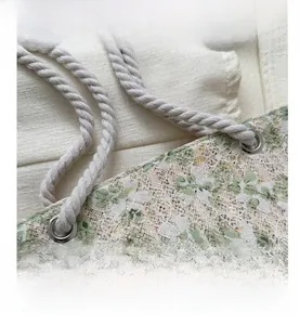 Detail of floral lace tote bag featuring sturdy rope handles and metallic eyelets