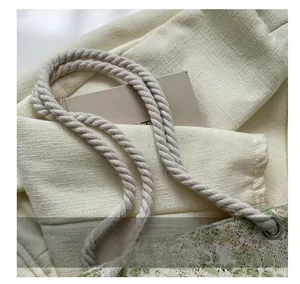 Close-up of woven cotton rope handles and floral lace texture on the canvas tote bag