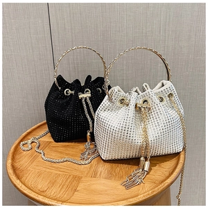 Detail of elegant rhinestone bucket bag with metal ring handle and tassel drawstring