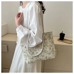 Close-up of green floral lace tote bag with white woven rope shoulder straps