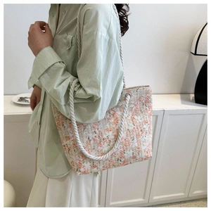 Close-up of floral canvas tote bag with white rope straps and metal ring details