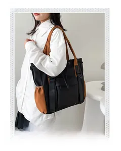 Woman wearing a large black and brown color-block tote bag with a practical shoulder strap