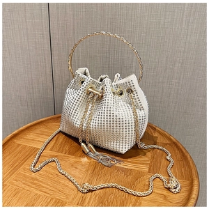 Detail view of rhinestone bucket bag with golden round handle and drawstring closure