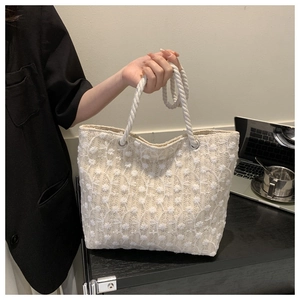 Detailed view of white floral lace tote bag with thick rope handle in office setting