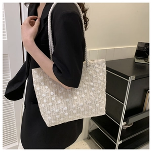 Detailed close-up of white lace tote bag with floral embroidery and rope handles