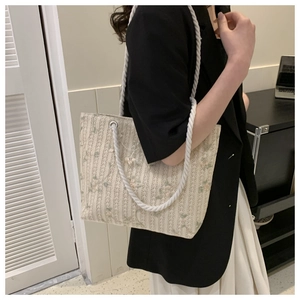 Close-up of floral woven tote bag with cotton rope handles and silver metal grommets