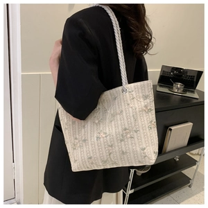 Close-up of floral embroidery on canvas tote bag with rustic white rope handles