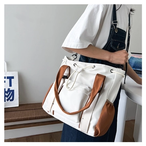 Canvas tote bag detail with brown strap handle and drawstring closure for daily commute
