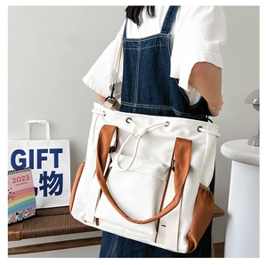 Detail of canvas tote bag with contrast brown straps and drawstring closure shown on model
