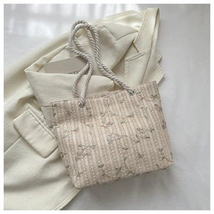 Detail shot of a woven tote bag with floral embroidery and thick cotton rope handles