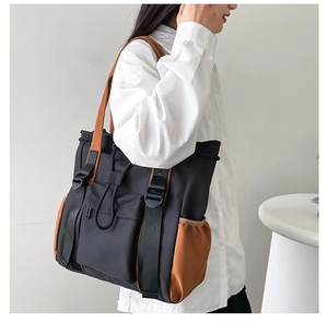 Detail view of a large contrast color tote bag showing side pockets and utility style