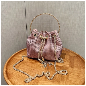 Pink rhinestone bucket bag detail with golden metal handle and woven chain strap