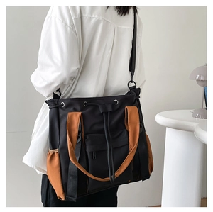 Detailed side view of the large capacity color block tote bag worn as a shoulder bag