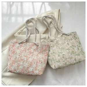 Detail of floral lace woven tote bags in pink and green with white cotton rope handles