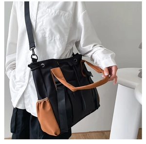 Close-up of black and khaki nylon tote bag showing adjustable straps and multi-pocket details