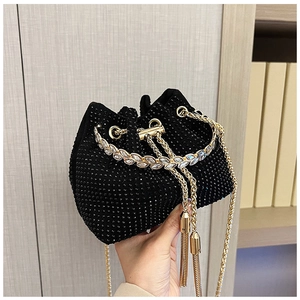 Detail of black rhinestone bucket bag with golden tassel drawstring and crystal leaf handle