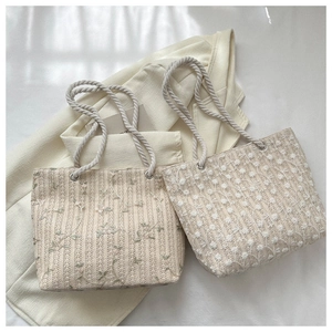 Detailed view of woven tote bags featuring floral embroidery and cotton rope handles