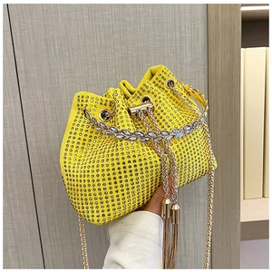 Detail of yellow bucket bag with sparkling crystals, golden handle and chain strap