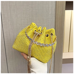 Close-up of yellow rhinestone bucket bag with golden chain drawstring and tassel