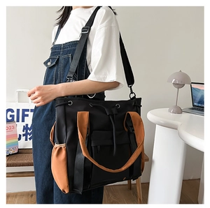 Close-up of a black and orange large capacity tote bag worn by a model in an office setting